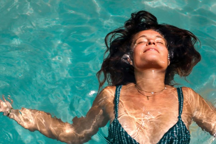 mujer tumbada sobre el agua mojandose el cabello dañado