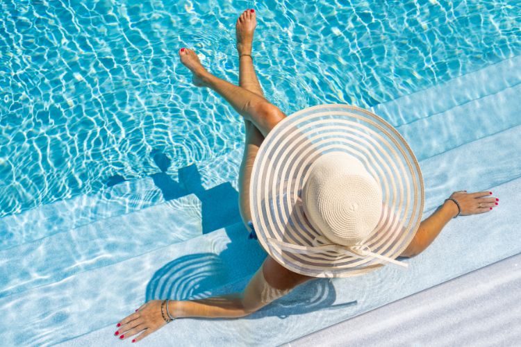 mujer tomando el sol en la piscina con un sombrero